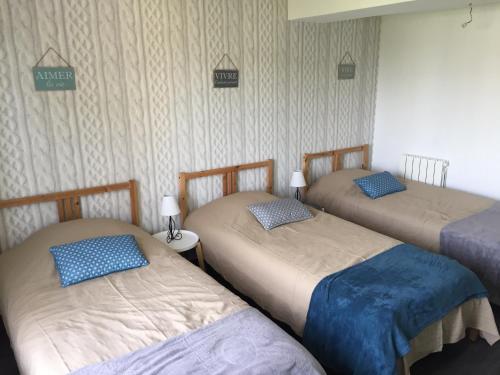 a room with three beds with blue pillows on them at La légende Men Marz 1er étage- Centre-ville Brignogan-Plages , 300 m des plages in Brignogan-Plages