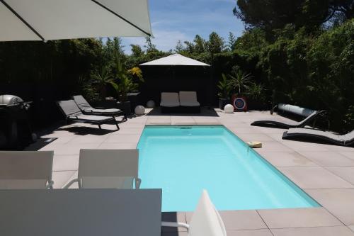 une piscine avec des chaises et un parasol dans l'établissement Magnifique Villa californienne avec piscine privative, à Antibes