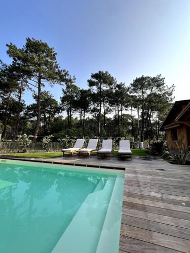un groupe de chaises longues assises à côté d'une piscine dans l'établissement Villa Piñhat, à Lège-Cap-Ferret