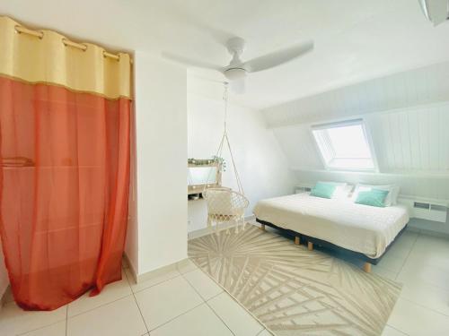 a bedroom with a bed with orange curtains and a window at Duplex-SeaYa-CentreVille&Marina in Marigot