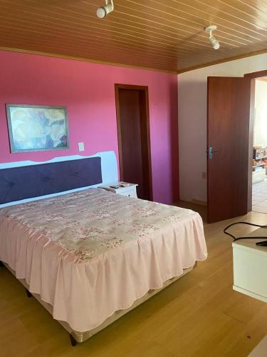 a bedroom with a large bed and a pink wall at Sobrado 263 in Jaguarão