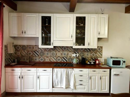 a white kitchen with white cabinets and a microwave at Etruscan Garden Apartment in Sutri