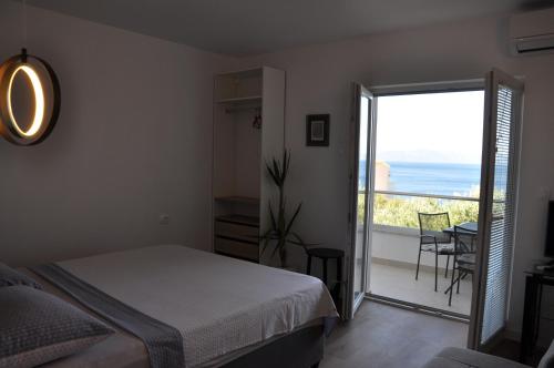 a bedroom with a bed and a balcony with the ocean at Apartments Gabriela in Drasnice