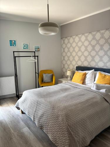 a bedroom with a bed and a yellow chair at Apartament Cesarski Agnes- bezpłatny parking- Resort Cesarskie Ogrody in Świnoujście
