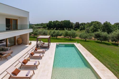 a swimming pool with lounge chairs and a house at Casa del oro in Vrsar
