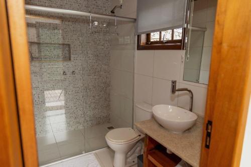 a bathroom with a shower and a toilet and a sink at Encontro dos Vales in Visconde De Maua
