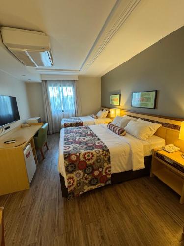 a hotel room with two beds and a flat screen tv at Alto Padrão - Cama Queen e Viuvão no Hotel Let's Idea in Brasilia