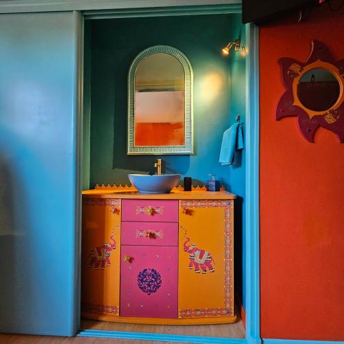 La salle de bains est pourvue d'un lavabo et d'une commode avec un miroir. dans l'établissement Le Domaine des Sources, à Landévant