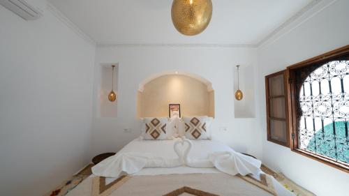 a bedroom with a bed with white sheets and a window at Riad 2 Ksour Marrakesh in Marrakesh