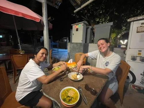 a man and woman sitting at a table eating food at Naca Homestay in Manado