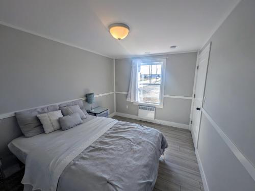 a white bedroom with a bed and a window at 3 bedroom 1 bathroom entire house in Glace Bay