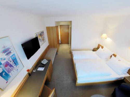 a hotel room with two beds and a flat screen tv at Hotel Maack in Seevetal