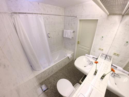 La salle de bains est pourvue d'un lavabo, de toilettes et d'une baignoire. dans l'établissement Hotel Maack, à Seevetal