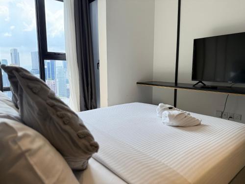 a bedroom with a bed with a television and towels at GriffinS Grove at Axon Residence Bukit Bintang in Kuala Lumpur