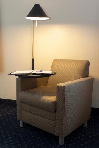 a chair and a lamp in a room with a table and a lamp at Hotel Focus SFO in South San Francisco