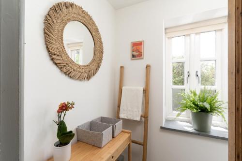 a mirror on a wall above a table with a box at Idyllic hideaway with hot tub, gym & gamesroom in Penzance