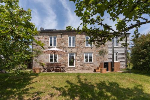 an external view of a stone house with an umbrella at Idyllic hideaway with hot tub, gym & gamesroom in Penzance