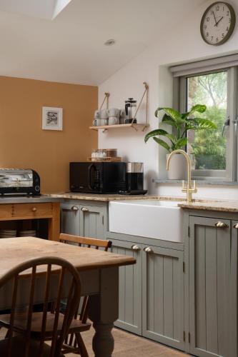 a kitchen with a table and a clock on the wall at Idyllic hideaway with hot tub, gym & gamesroom in Penzance