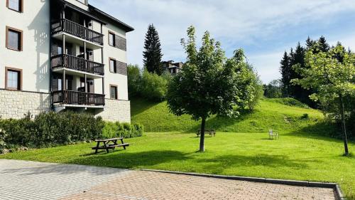 a park with a bench in front of a building at Apartmán Špindl 101čka Dalibor II in Špindlerův Mlýn