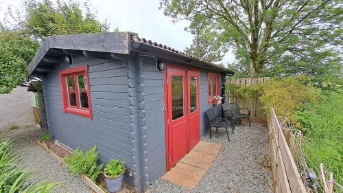a small shed with a red door and a person at The Cosy Cabin in Portree