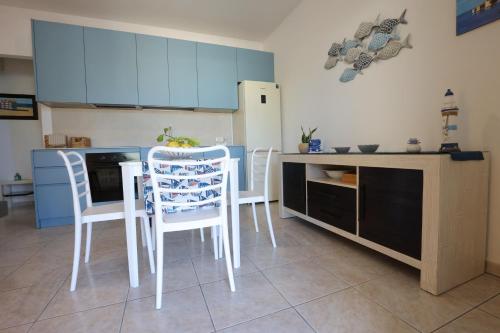 a kitchen with white chairs and a table and a refrigerator at La casetta di Gabry - Torre Specchia Ruggeri in Torre Specchia Ruggeri