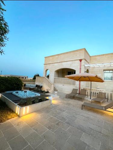 オートラントにあるBianco Mare Villaのスイミングプールと傘付きの建物