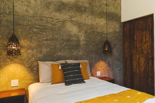 una camera da letto con un letto con tre cuscini sopra di Casa Pakal-Cozy Cottage Near Cerritos Beach a San Carlos