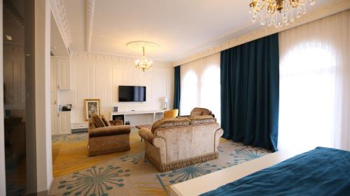 a bedroom with a living room with a couch and a tv at Grand Hotel Belushi in Boge