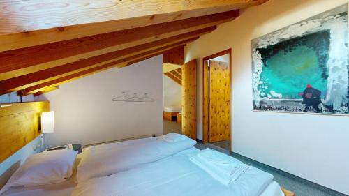 a bed in a bedroom with a painting on the wall at Flurina 45 in Silvaplana