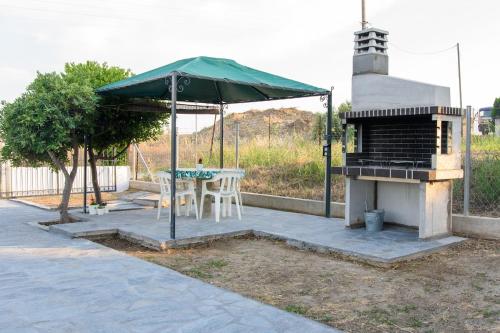 an outdoor grill with a table and an umbrella at Oxygen Nest in Nea Kalikratia