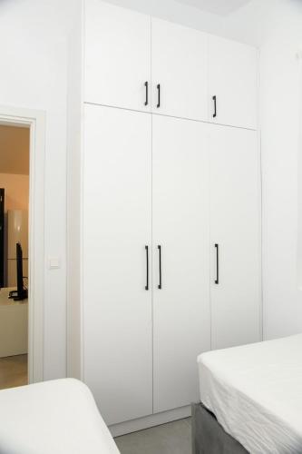a white bedroom with two beds and white cabinets at Oxygen Nest in Nea Kalikratia
