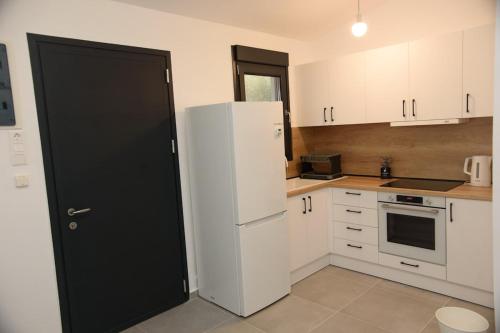 a kitchen with white cabinets and a white refrigerator at Oxygen Nest in Nea Kalikratia