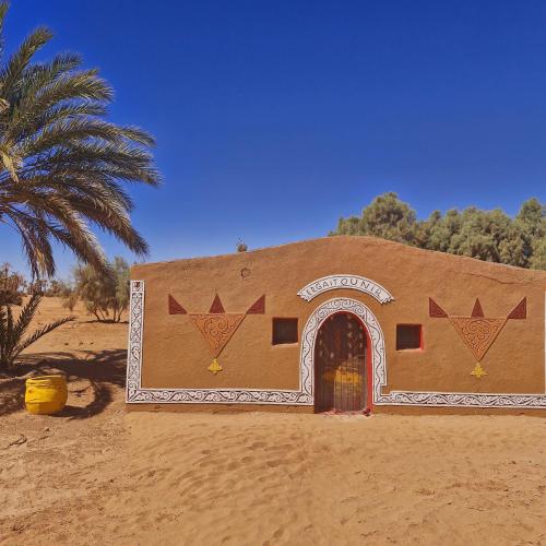 a building in the middle of the desert with a palm tree at Luxury tent VIP GHEZLAN in Mhamid