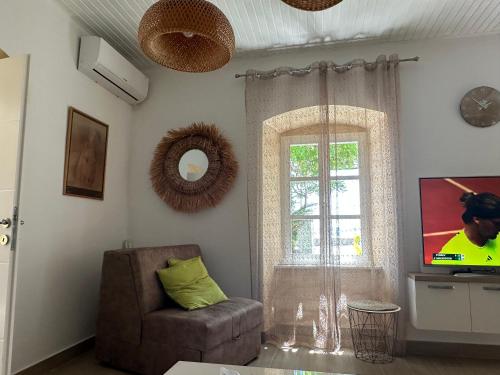 ein Wohnzimmer mit einem TV, einem Stuhl und einem Fenster in der Unterkunft Zanzibar in Savina