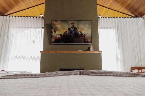 a bedroom with a bed with a tv on the wall at Encontro dos Vales in Visconde De Maua