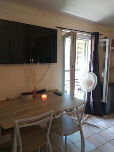 d'une table à manger avec des chaises et une bougie. dans l'établissement Appartement 1 pièce à deux pas de la plage et à 10min du centre ville et la gare 15 minutes de l'aéroport, à Nice
