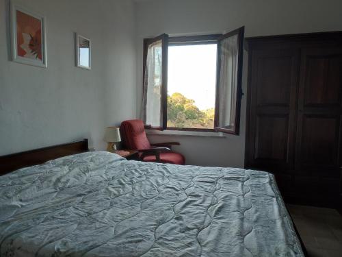 a bedroom with a bed and a chair and a window at Borgo Ingurtosu in Ingurtosu