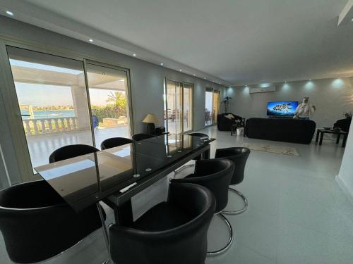 a living room with a glass table and chairs at فيلا فاخرة بشاطئ خاص وإطلالة ساحرة على البحيرة in El Alamein