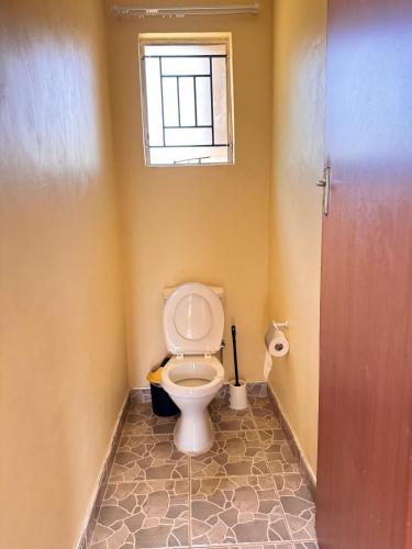 a bathroom with a toilet with a window at Takonda BnB in Zomba