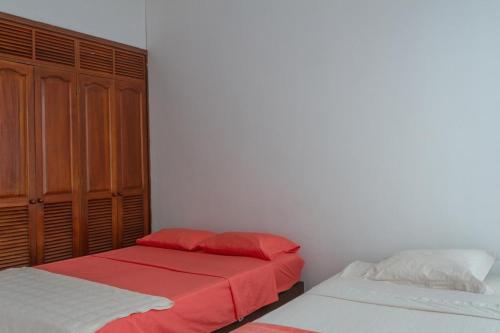 a bedroom with two beds with red and white sheets at Hermosa casa en el centro de Ricaurte in Ricaurte