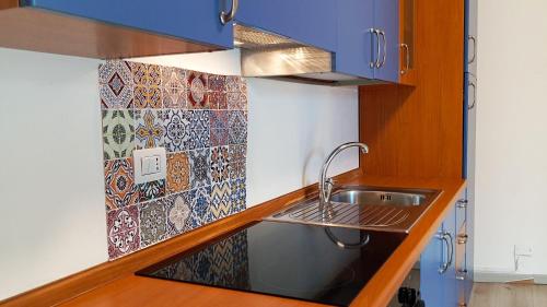 a kitchen with a sink and a tile wall at Medoro Piazza Roma Rooms in Milazzo