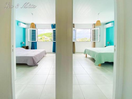 Habitación con 2 camas y paredes azules. en Bungalow bord de mer, en Le Robert