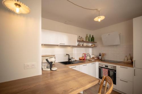 une cuisine avec des armoires blanches et un comptoir en bois dans l'établissement Maison Valentine, à Castelnau-sur-lʼAuvignon