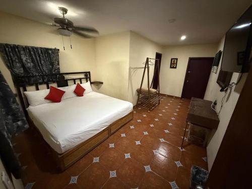 a bedroom with a white bed with red pillows at Hotel Hacienda Tonalmain, Central Nueva in Guadalajara