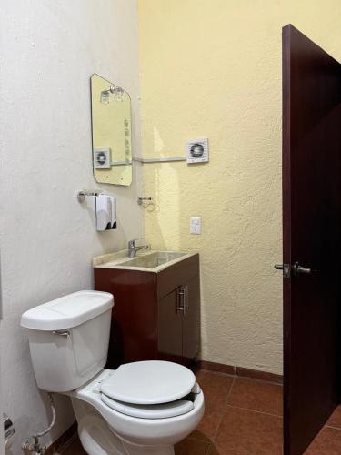 a bathroom with a white toilet and a sink at Hotel Hacienda Tonalmain, Central Nueva in Guadalajara