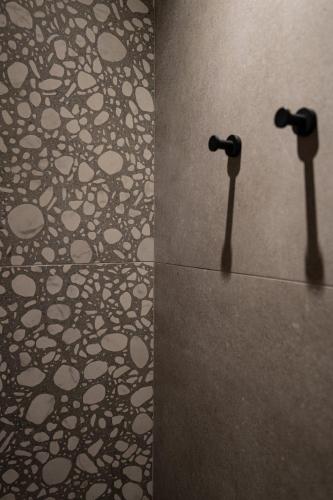 a bathroom with a wall with a mirror and a tile floor at Madonna del Mare City in Chania Town