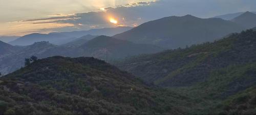 a view of a mountain range with the sun setting in the background at Ferme Dar Aicha green Bellouta in Bellouta