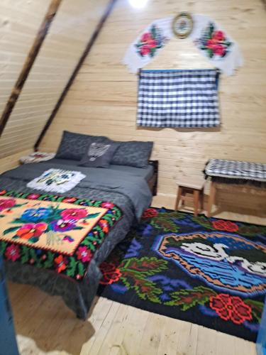 a bedroom with a bed and a rug and a table at Casuta din padure in Breb