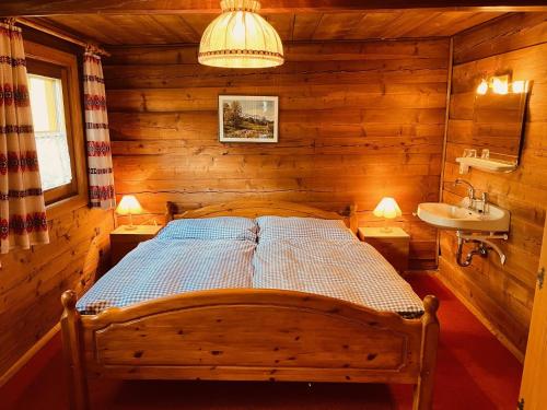 a bedroom with a bed and a sink in a log cabin at Ferienhaus Unterkircher-Wallner in Heiligenblut