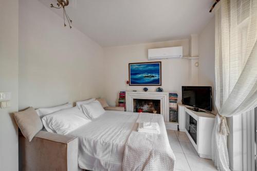 a white bedroom with a bed and a tv at Aura in Piraeus